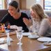 Friends celebrating a birthday with cake and laughter in a cozy café setting.